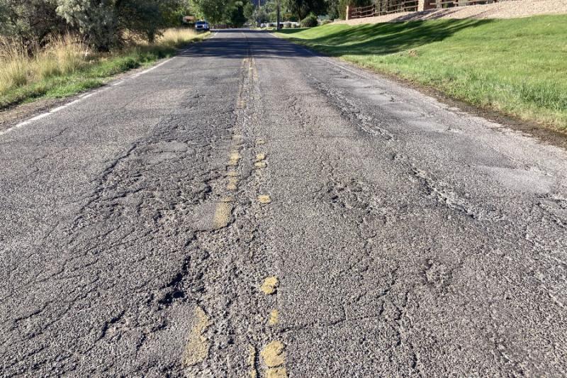 Grey cracked road in bad condition. 