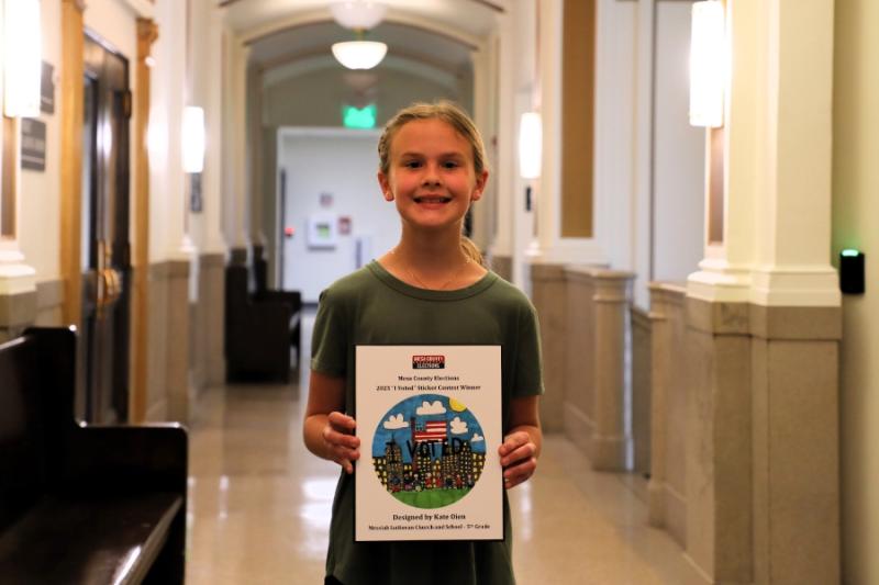 A child smiling holding a framed drawing. 