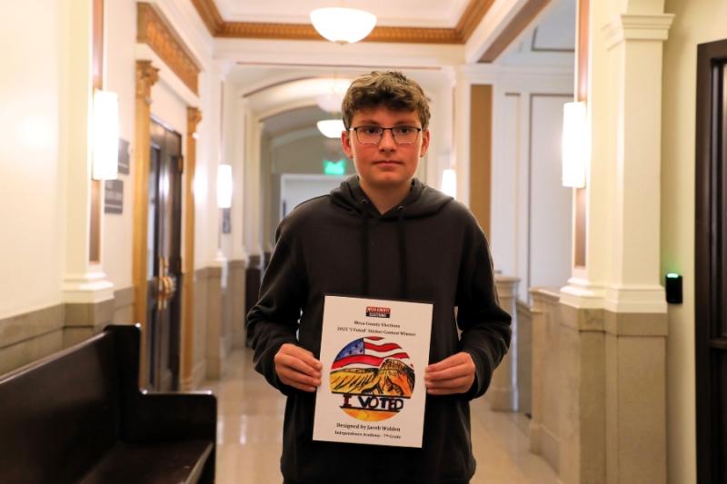 A child smiling holding a framed drawing. 