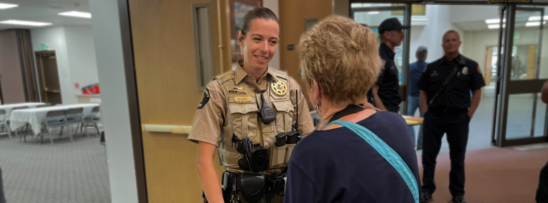 Deputy Savannah Leidy smiles as she talks with a female senior citizen whose back is to the camera.