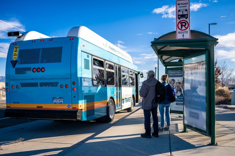Riders preparing to board a Grand Valley Transit bus at a bus stop.