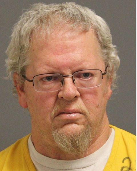 Inmate photo of Patrick Sneddon wearing glasses and a yellow jumpsuit. 