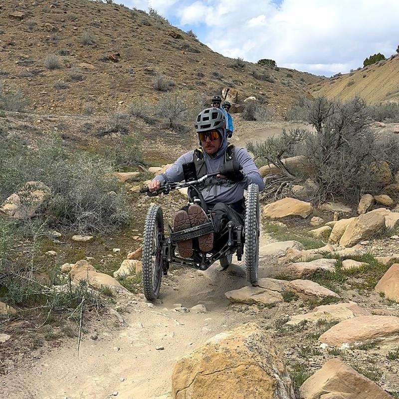 This person is biking a trail at North Fruita Desert using a specially modified electric motor assisted tricycle called an adaptive mountain bike.