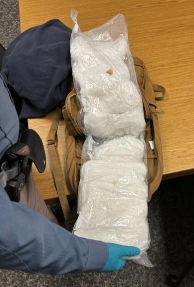Trooper holding open backpack showing pounds of meth.