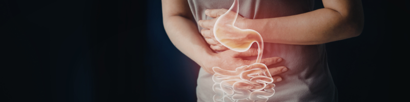 A person holds their stomach, with a glowing illustration of the stomach and intestines superimposed on their body, indicating digestive distress.