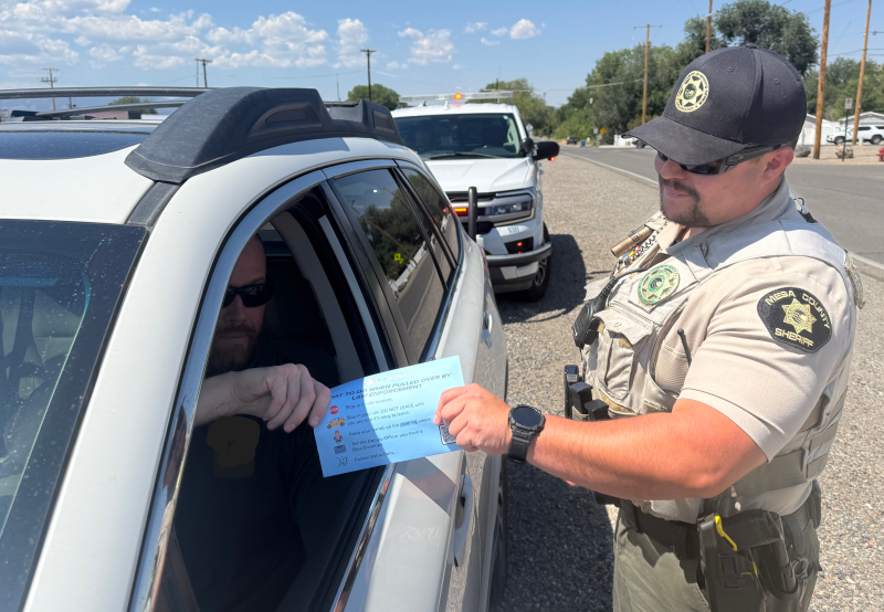 Driver handing a blue enevelope to deputy on a traffic stop