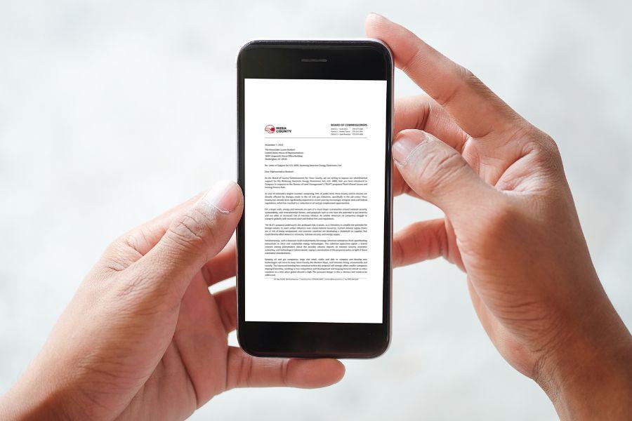 Hands holding smart phone displaying letter.