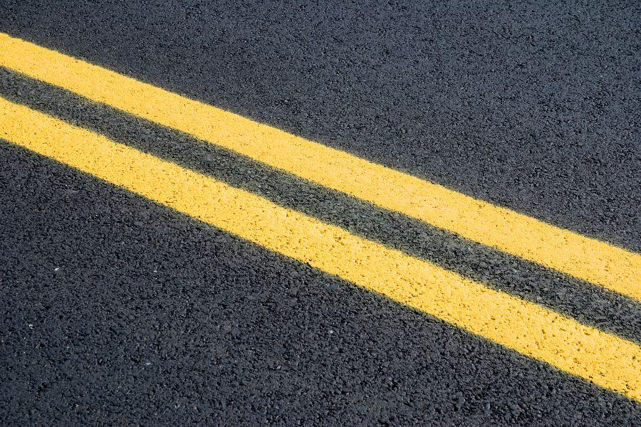 Black road with fresh yellow double stripes. 