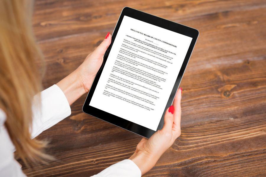 Two hands holding black iPad displaying a resolution. 