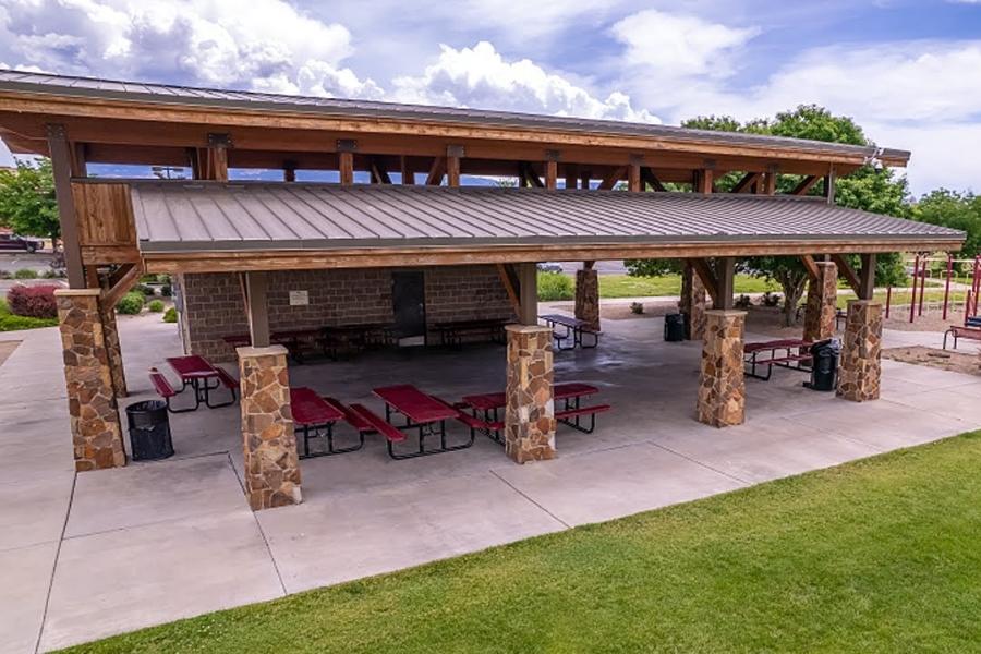 Outdoor structure covers red picnic tables. 