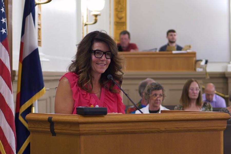 Woman stands at lectern with a smile on her face. 