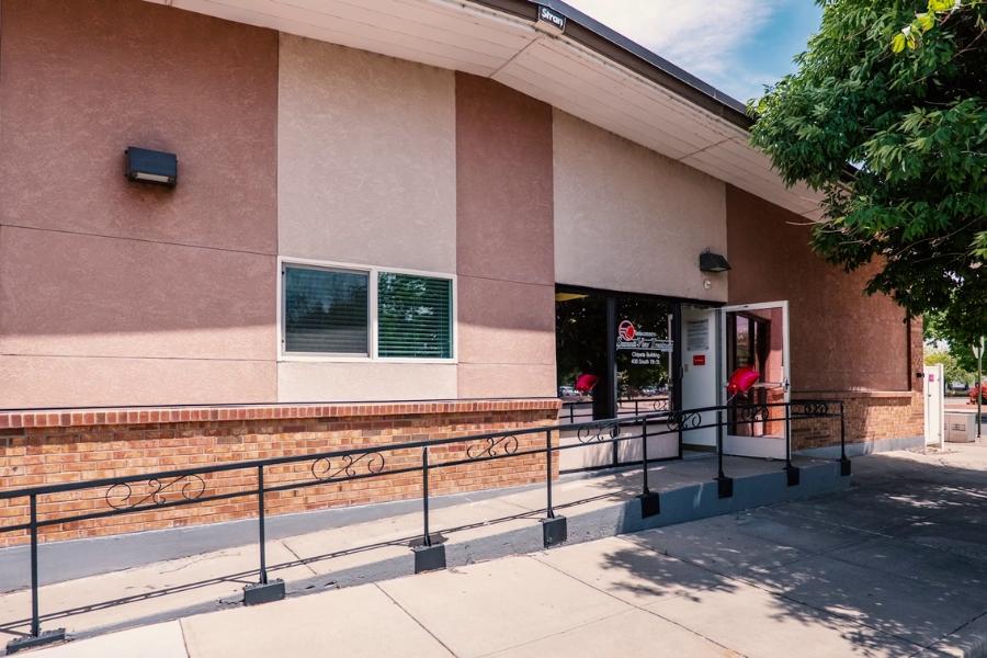 Tan stucco building with Mesa County logo on front door.