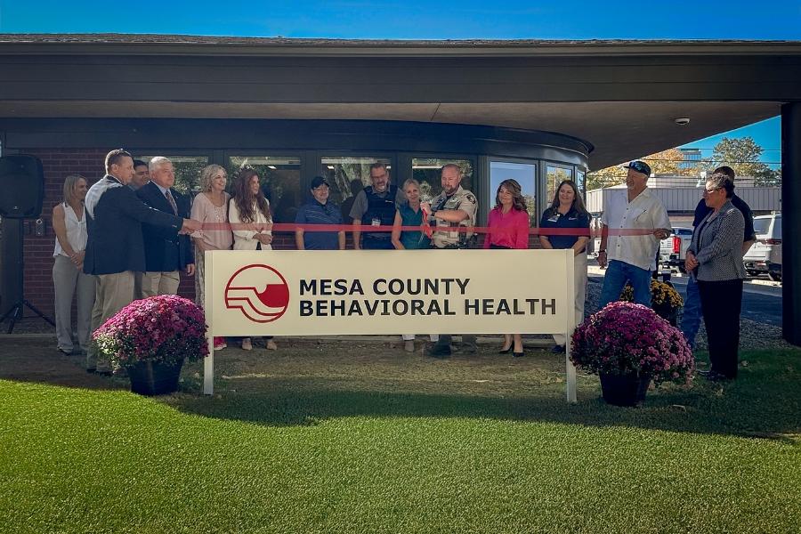 Group of people in front of "Mesa County Behavioral Health" sign and building. 