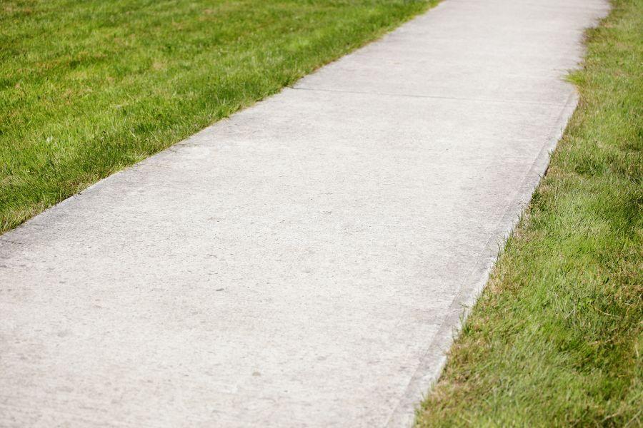 Concrete sidewalk surrounded by green grass. 