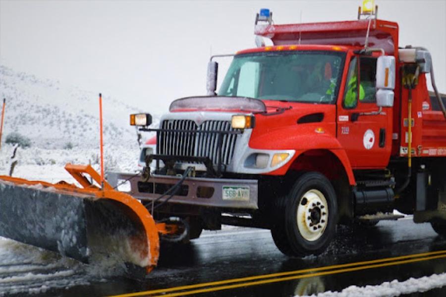 Red Mesa County snow removal truck on snowy road. 