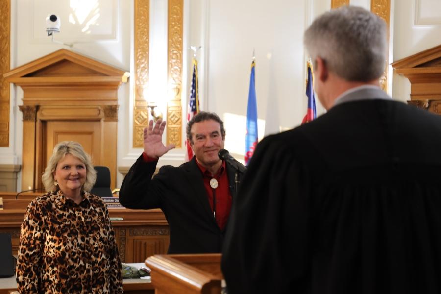 Man (Mesa County Commissioner JJ Fletcher) standing at microphone smiling and holding a notebook. 
