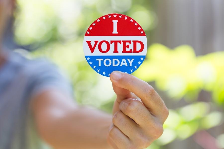 Blurry girl holding red, white and blue sticker reading, "I VOTED TODAY."
