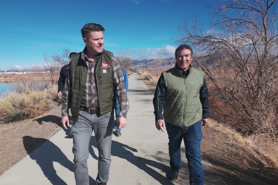 Two men walking on a sidewalk in open space. 