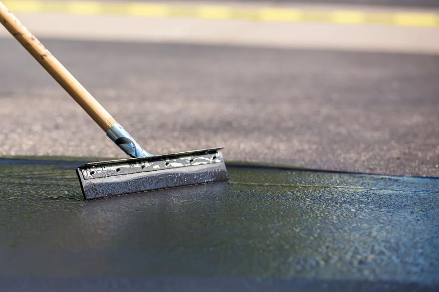 Squeegee going over fresh asphalt on road. 