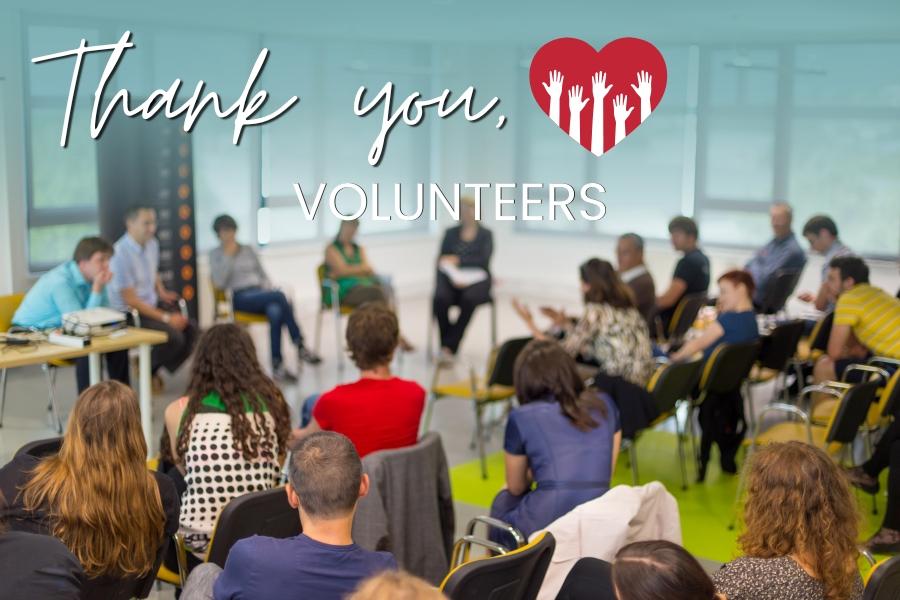 A group of people sitting a room with with white text reading, Thank you, volunteers. 