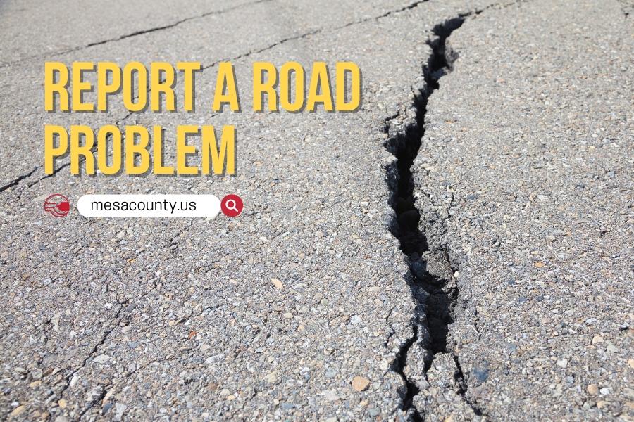A cracked road with yellow and black text reading, REPORT A ROAD PROBLEM, mesacounty.us, next to the red Mesa County logo. 