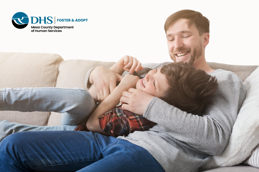 Kinship caregiver laughing with young boy on a couch.