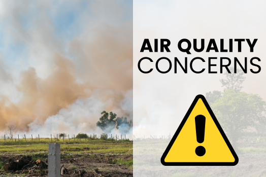 Plumes of smoke over grassy field with alert icon