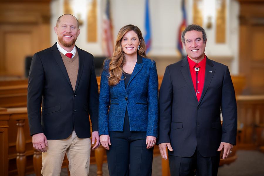 Three people in professional clothing standing next to each other smiling. 