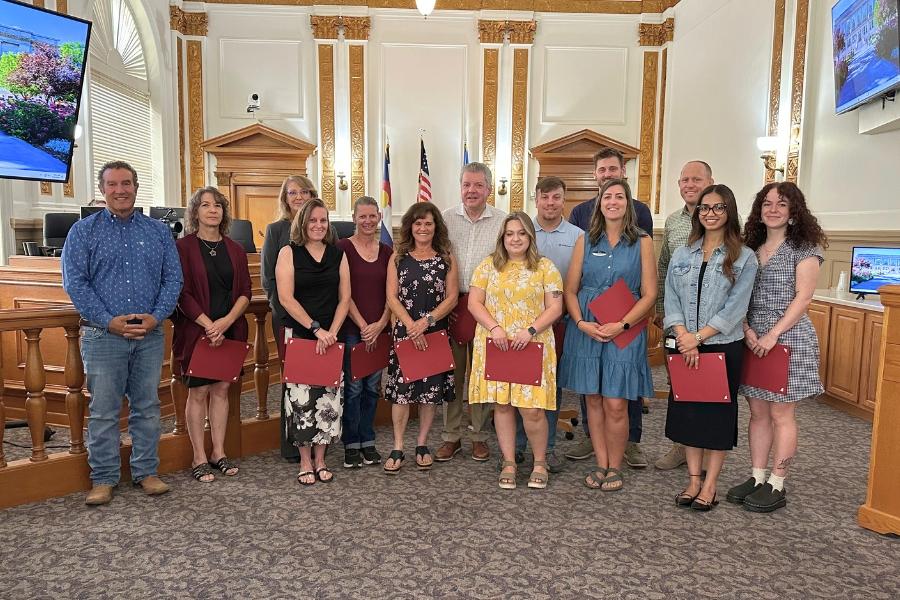 A group of people standing together, smiling, holding certificates. 