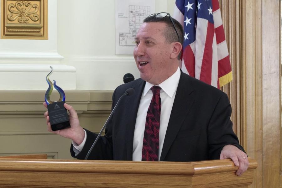 A man holding a trophy at a lectern. 