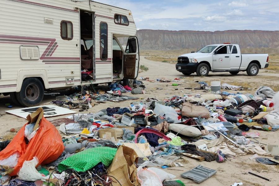 A pile of trash next to an RV and a Mesa County vehicle. 