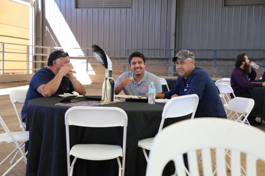 Three men sitting at a table, eating lunch. 