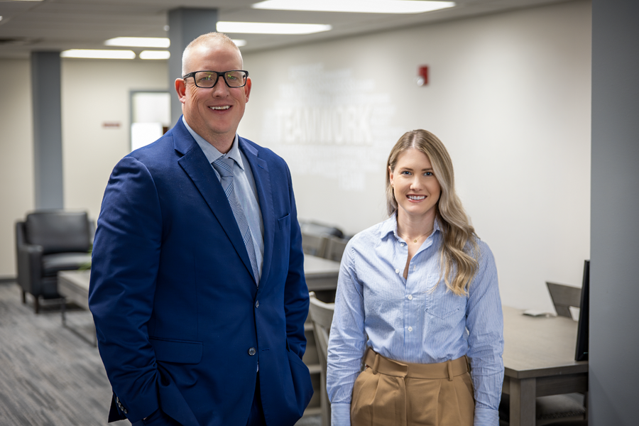 A man and a woman standing in an office, smiling. 