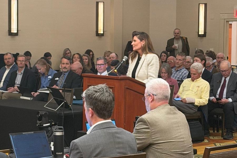A woman speaking at a lectern in front of an audience. 