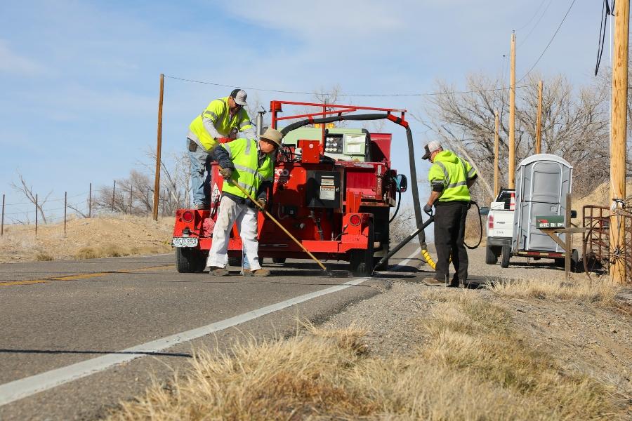 Three employees working on Mesa County roads next to a red truck. 