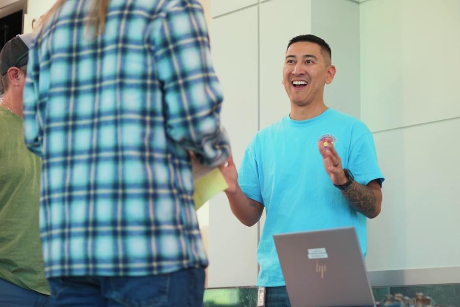 A man smiling and talking to a customer. 