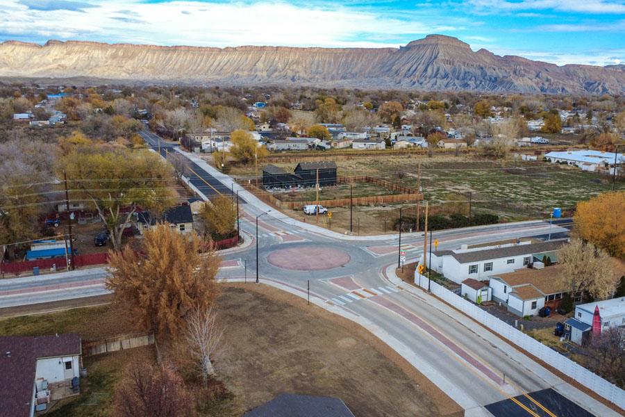 Aerial view of the new roundabout at 32 ½ Road and E Road in Clifton, showing widened roadway, sidewalks and surrounding neighborhood with the Book Cliffs in the background.