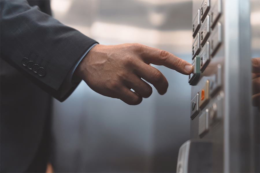 Close-up of a person pressing a button inside an elevator, highlighting accessibility and everyday use of public building features.