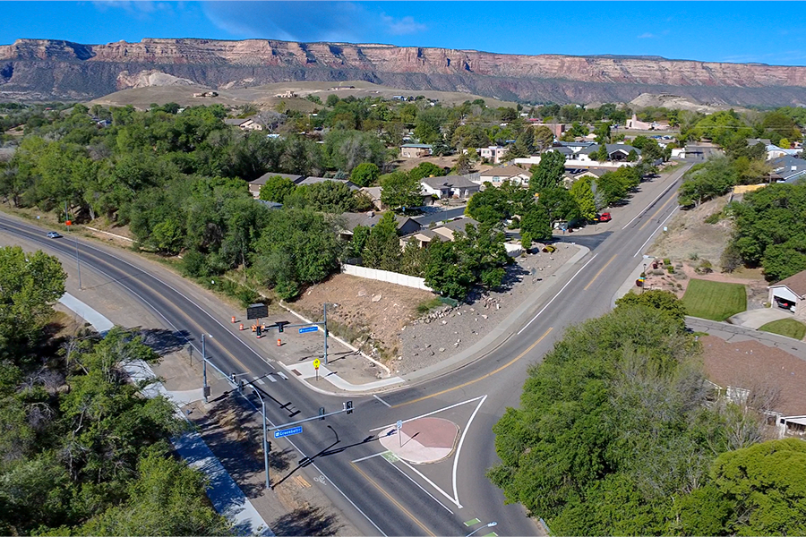 Aerial view of the intersection at 22 1/2 Road and Greenbelt Drive, showing surrounding neighborhood streets, sidewalks and nearby homes with the Colorado National Monument in the background.