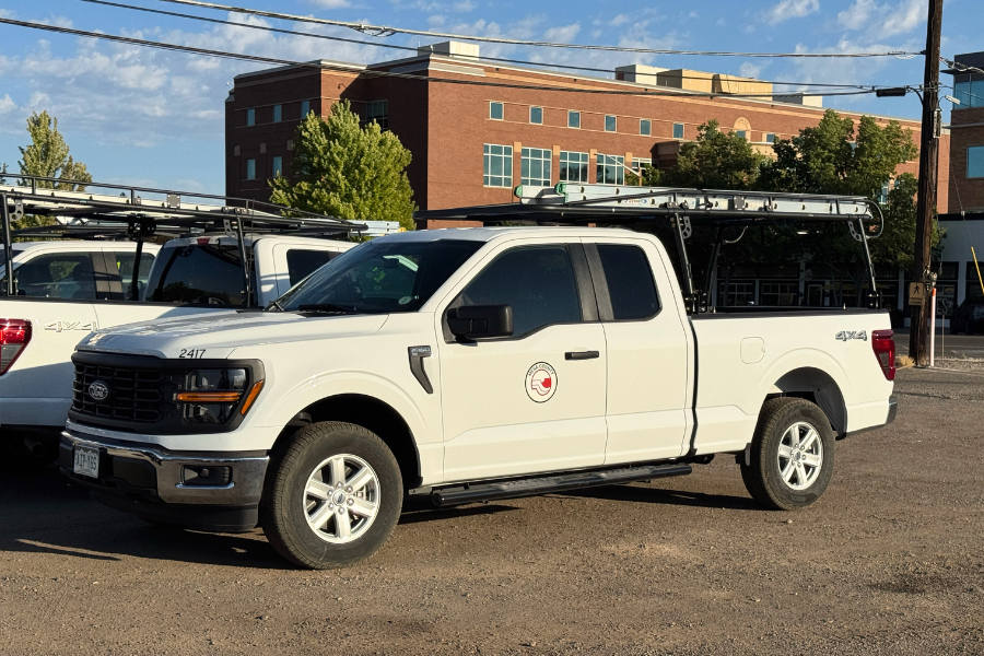  White Mesa County trucks equipped with ladder racks parked at the Mesa County Central Services Building.