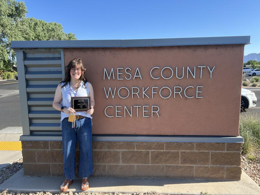 Jeana Brown posing with award in front of WFC sign
